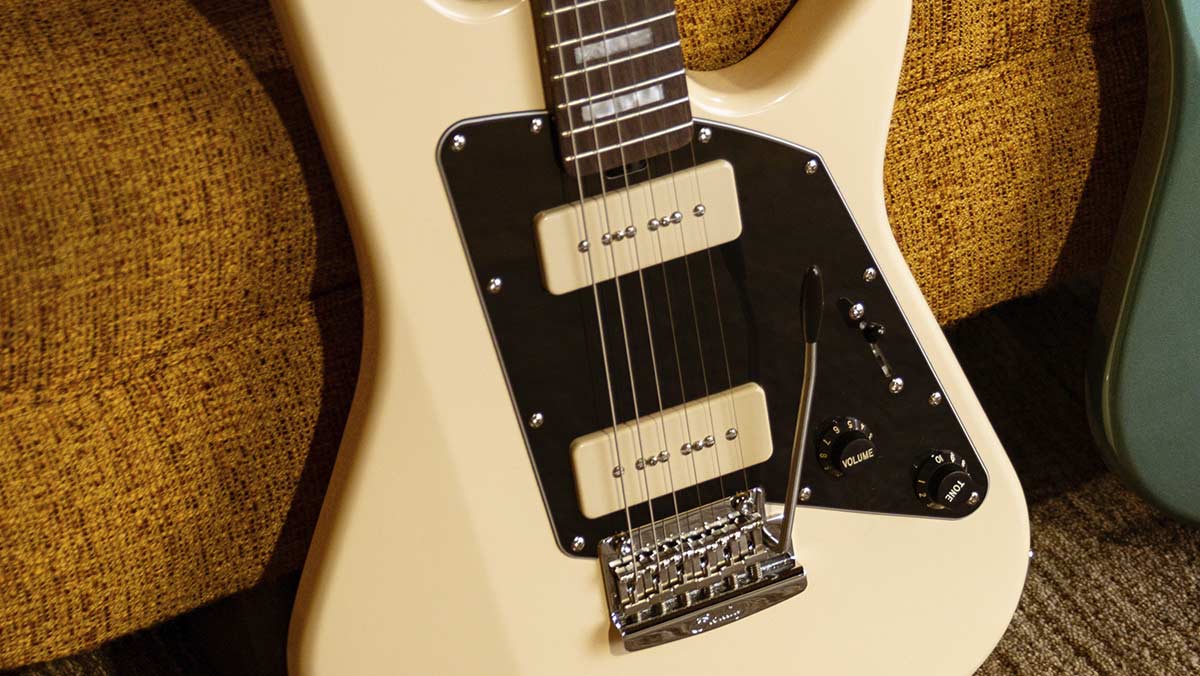 Closeup of a creme colored electric guitar with a black pickguard