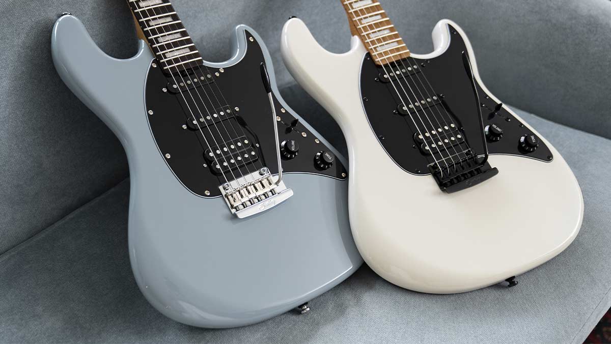 Two stratocaster-style electric guitars on a sofa