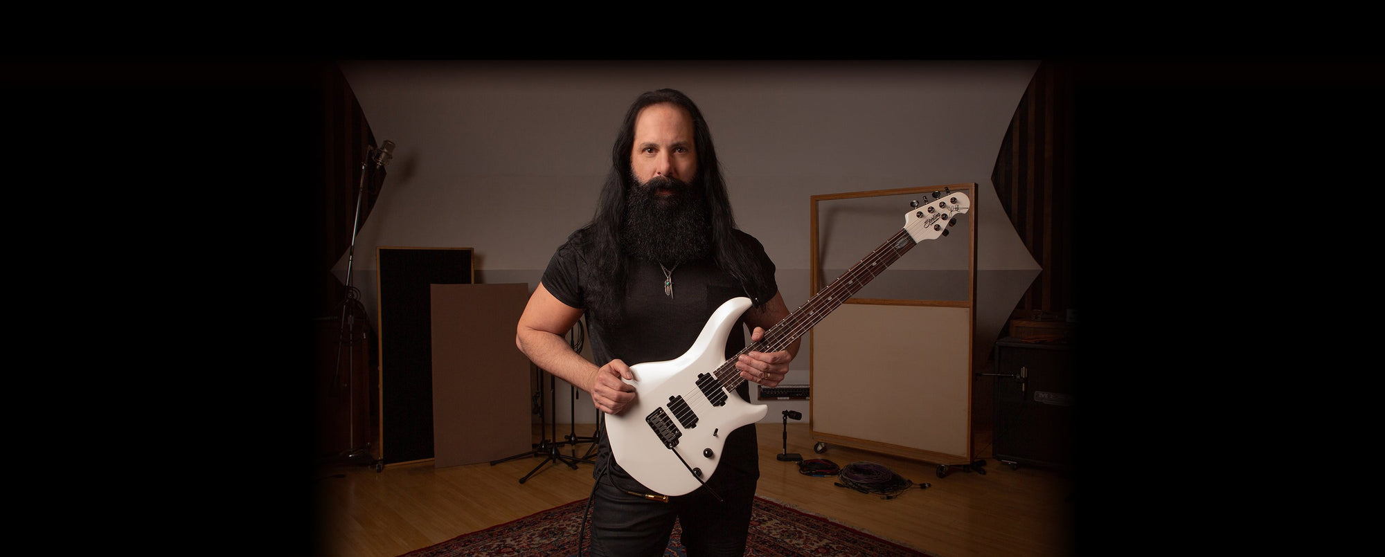 John Petrucci holding the Majesty 7 guitar in Pearl White.