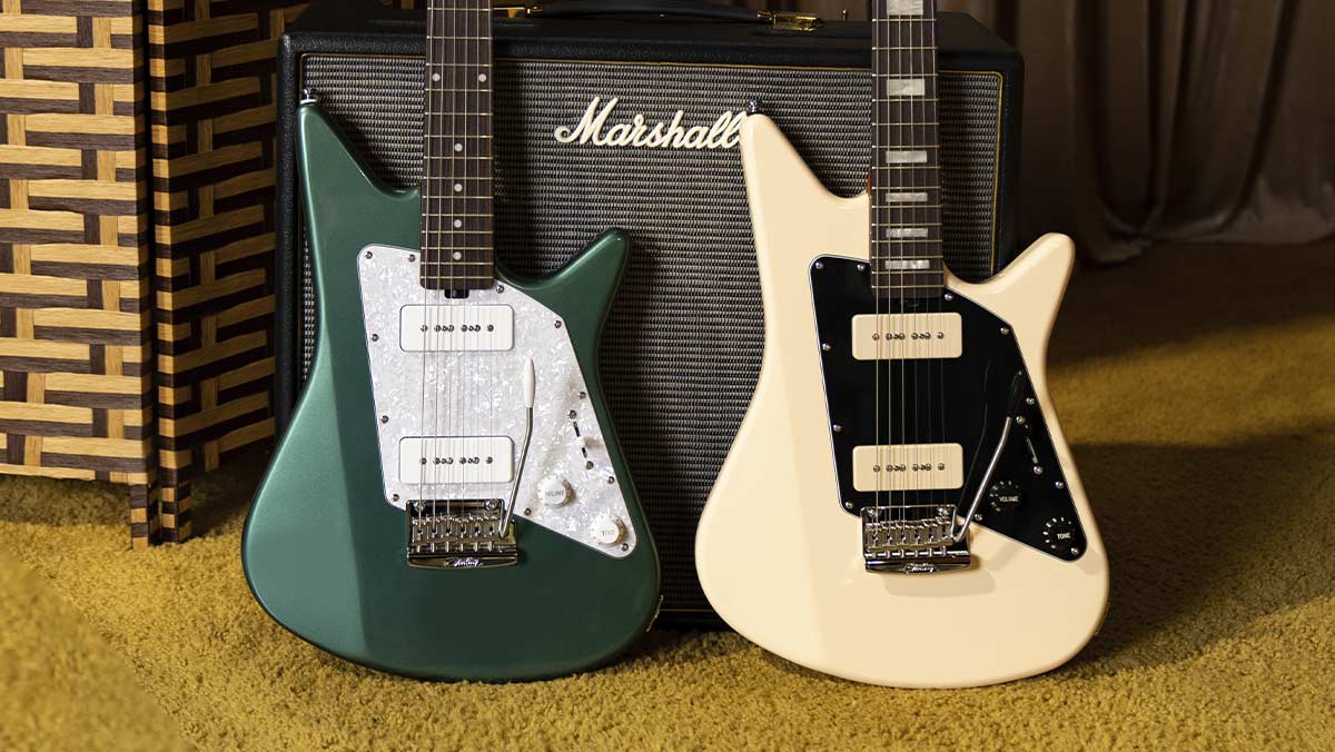 A green electric guitar and a creme electric guitar in front of an amp